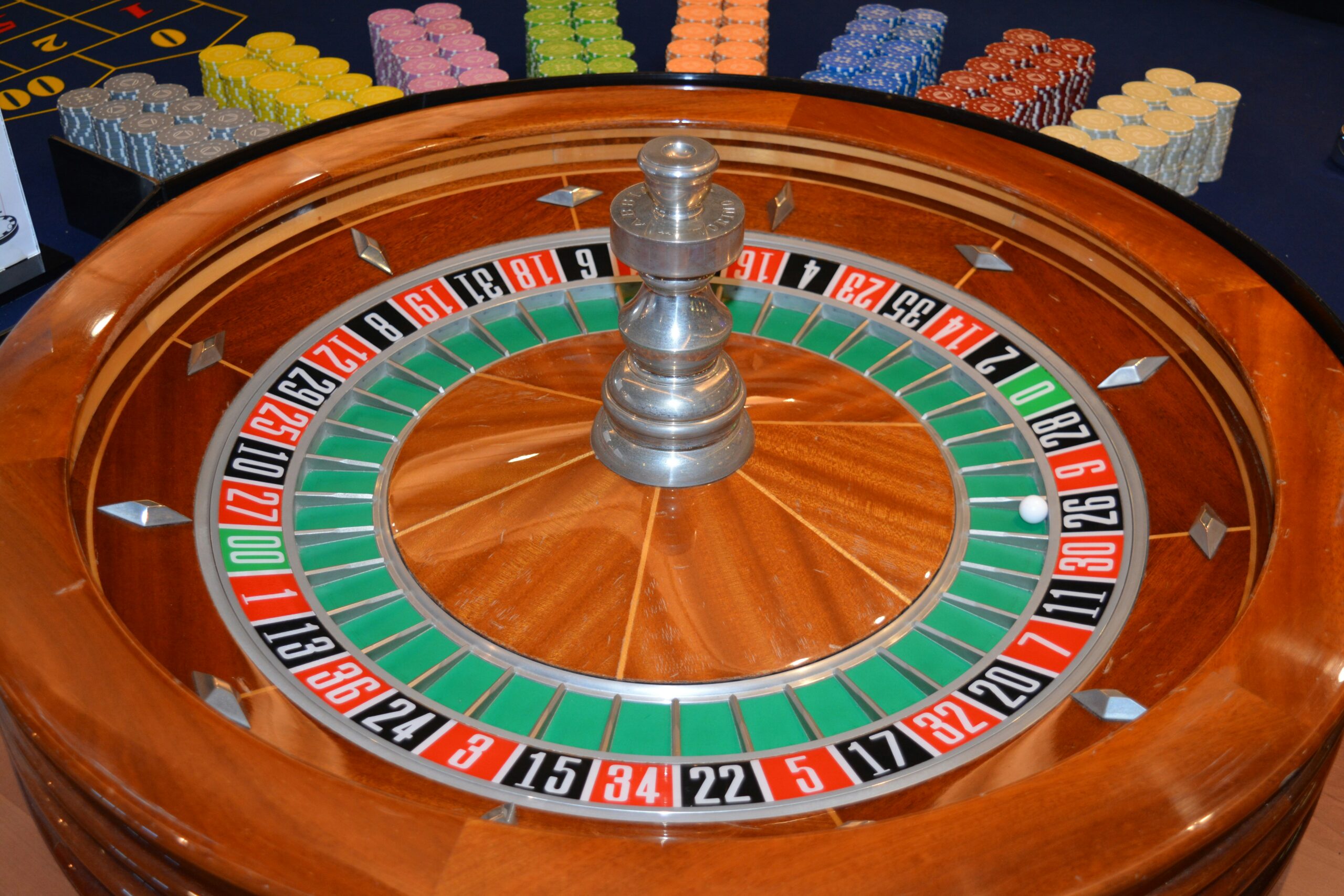 Roulette-Kessel von oben mit bunten Casino-Chips im Hintergrund